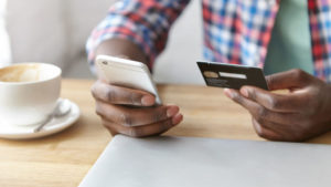 Young man paying for something on his phone with a credit card
