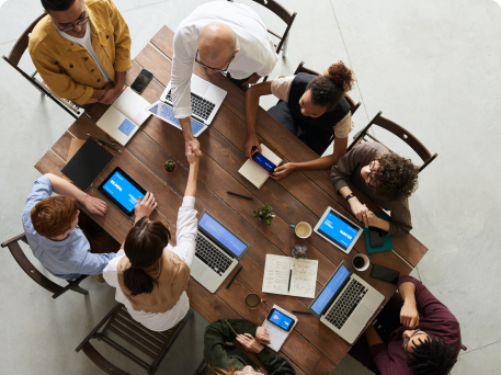 A Photo of a group of people with laptops sitting around a table collaborating