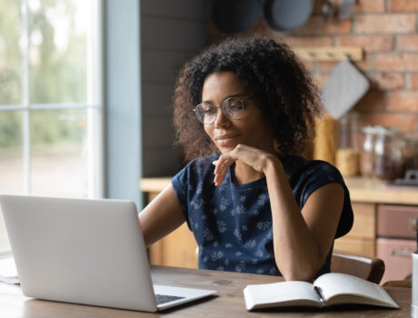 Close up focused African American woman in glasses using laptop