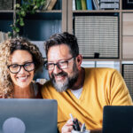 Happy adult couple work at home together with video conference computer